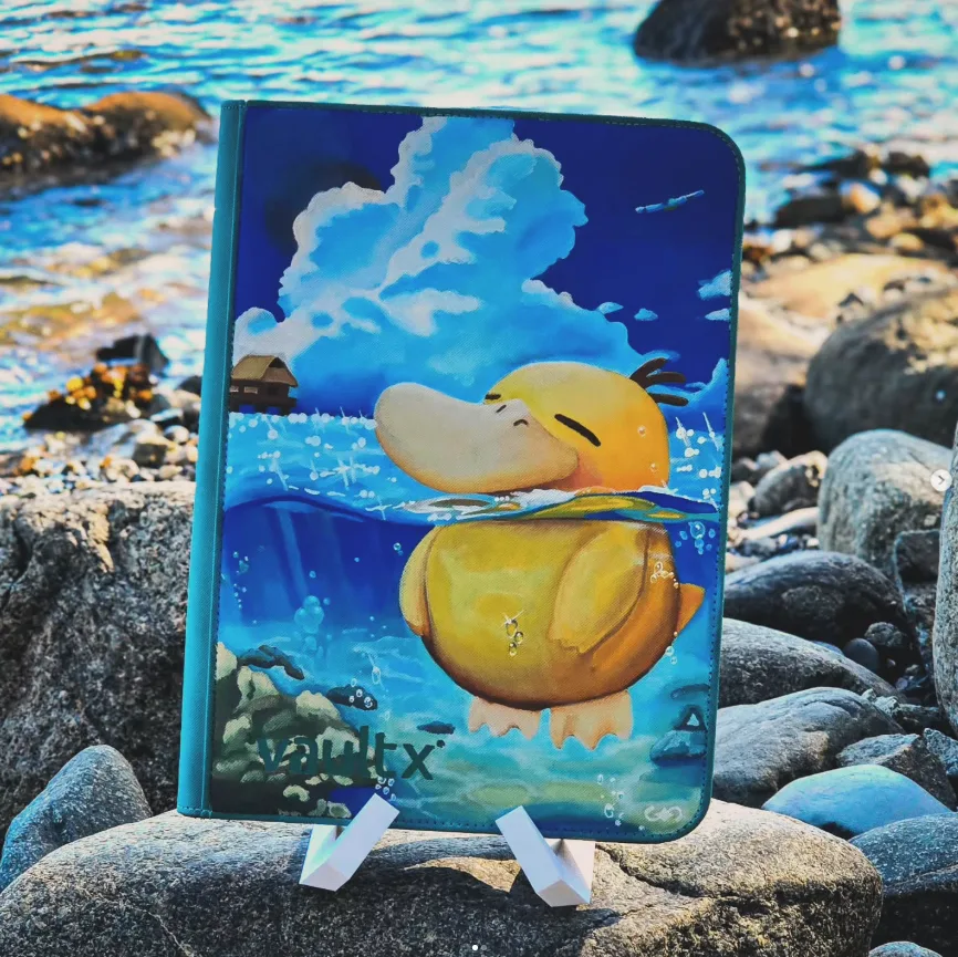 A hand-painted binder displayed on a stand among rocks beside the water